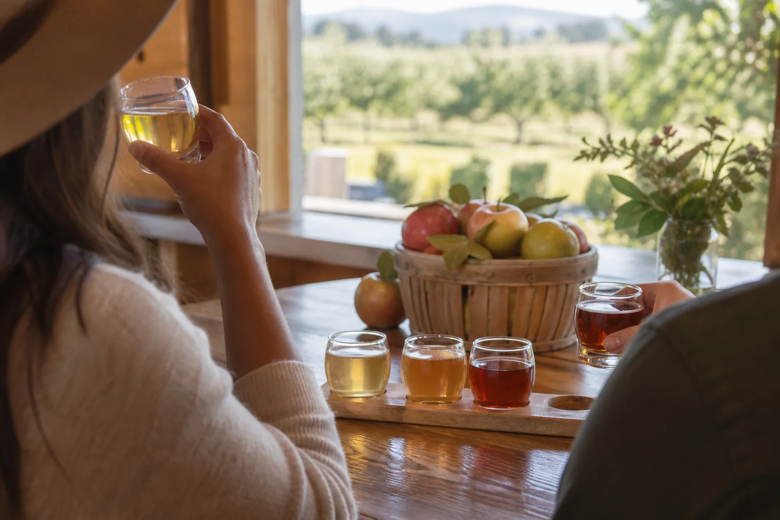 A rustic tasting room offers flights of hard cider beside orchard views and baskets of fresh apples.